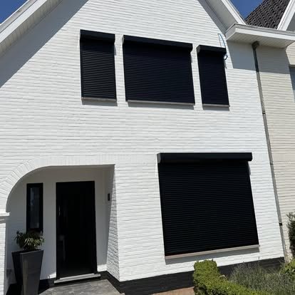 Zwarte rolluiken op een witte gevel