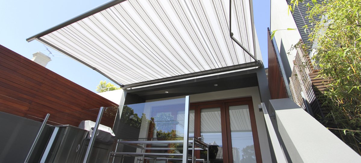 Knikarmscherm met gestreept doek boven een terras